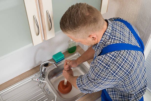 High Angle View Of Worker Pressing Plunger In Steel Kitchen Sink