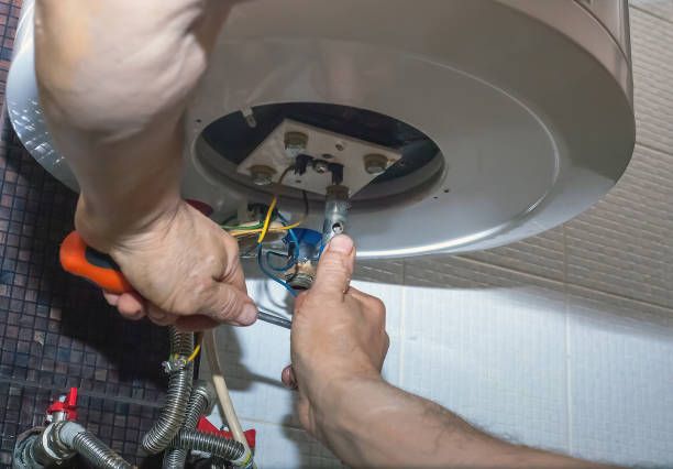 Plumber man repairing electric boiler in bathroom. Repairman hand are fixing broken water heater