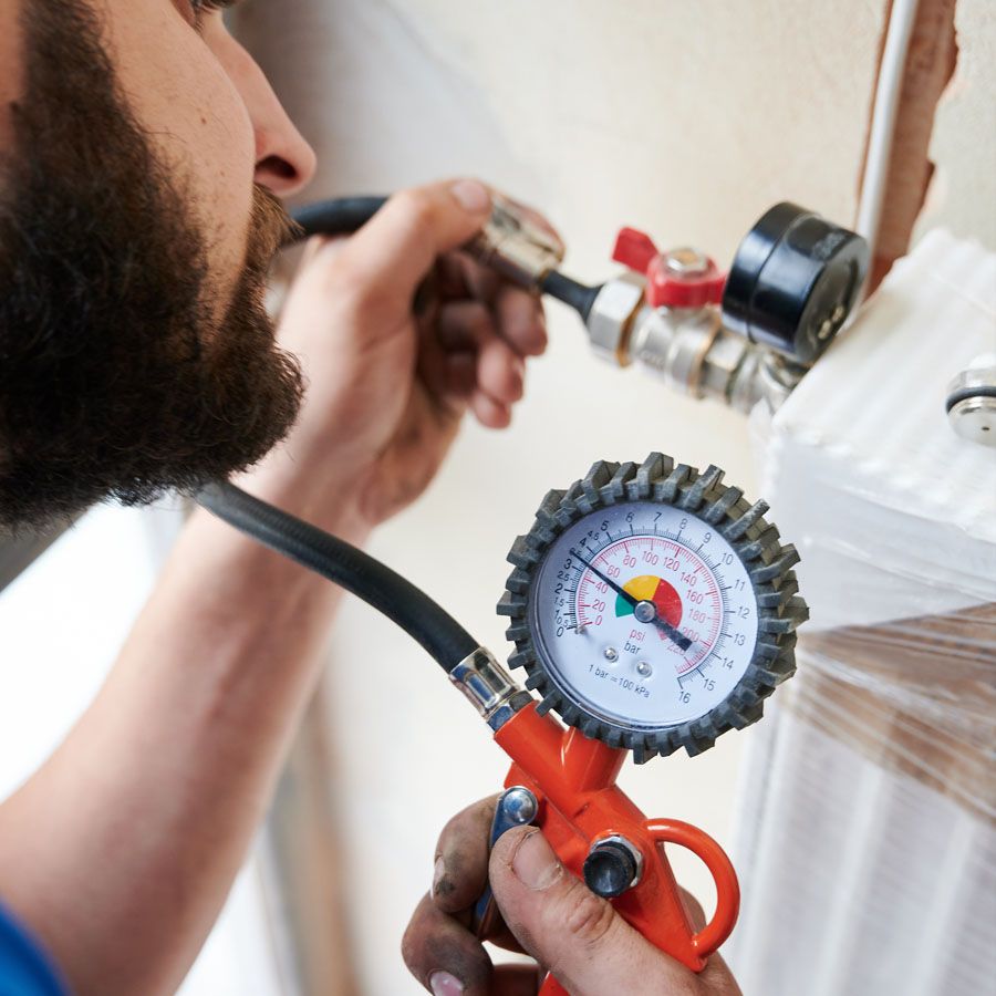 a plumber checking gas hot water system with his tools