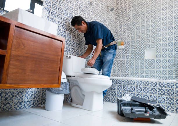 A plumber fixing a toilet in the bathroom