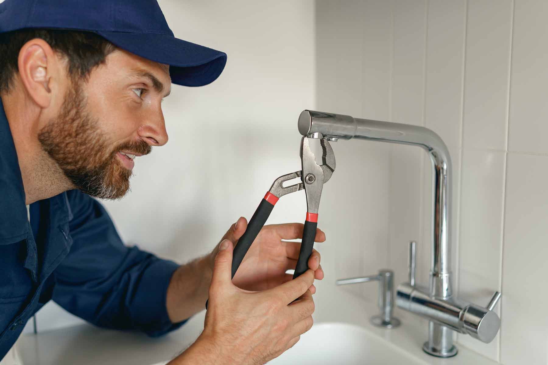 a plumber repairing tap with the help of his tool